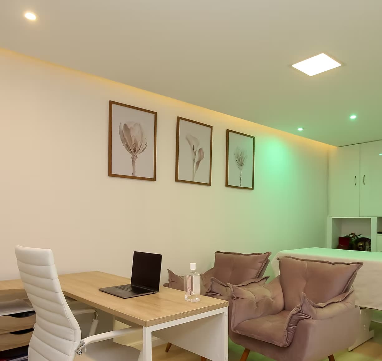 Consultório da clínica: mesa de atendimento, poltronas e maca, com iluminação suave